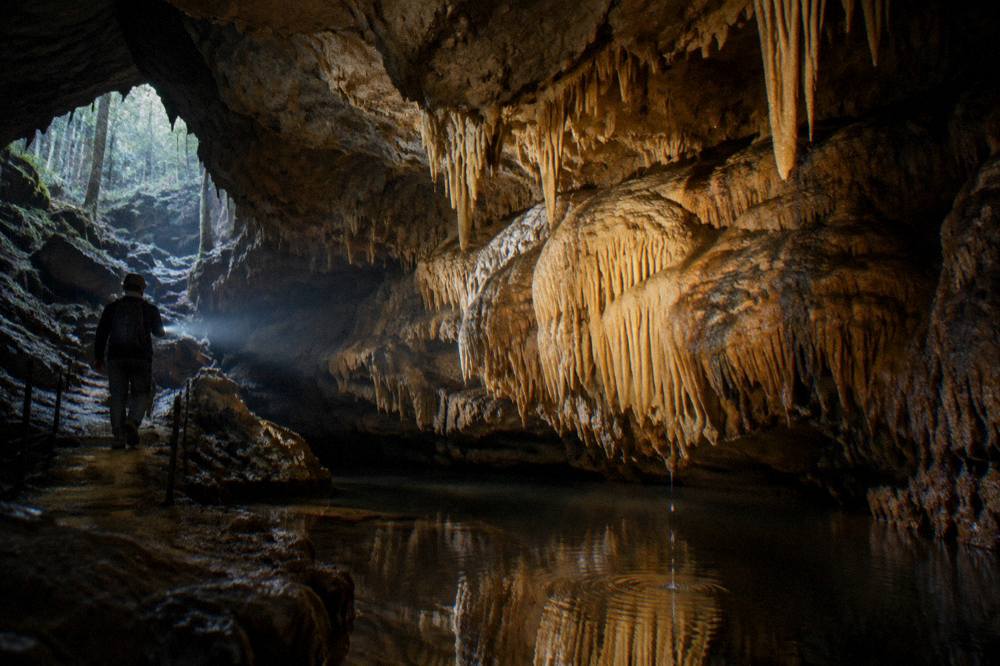 Stalactites and flowstone formations inside a lit limestone cave chamber