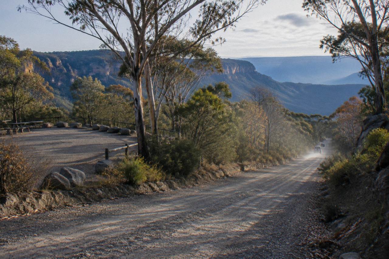 Unsealed gravel road winding through dry eucalypt forest toward the Glow Worm Tunnel carpark