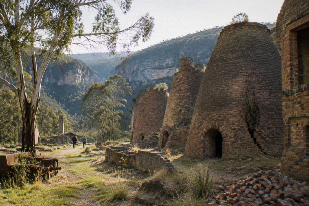 Old industrial stone ruins of beehive kilns standing among trees at Newnes