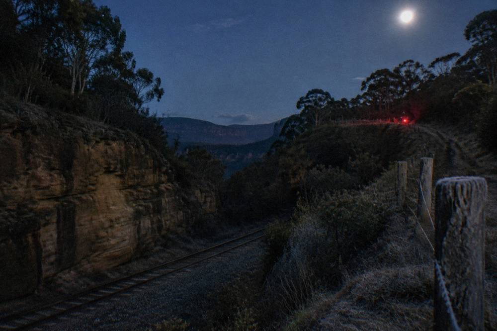 A bush track at night in the Blue Mountains with a faint red glow from headlamps ahead