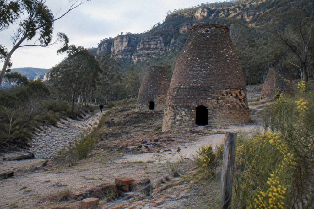 Ruins of old industrial brick kilns standing in open woodland beside a dry creek bed