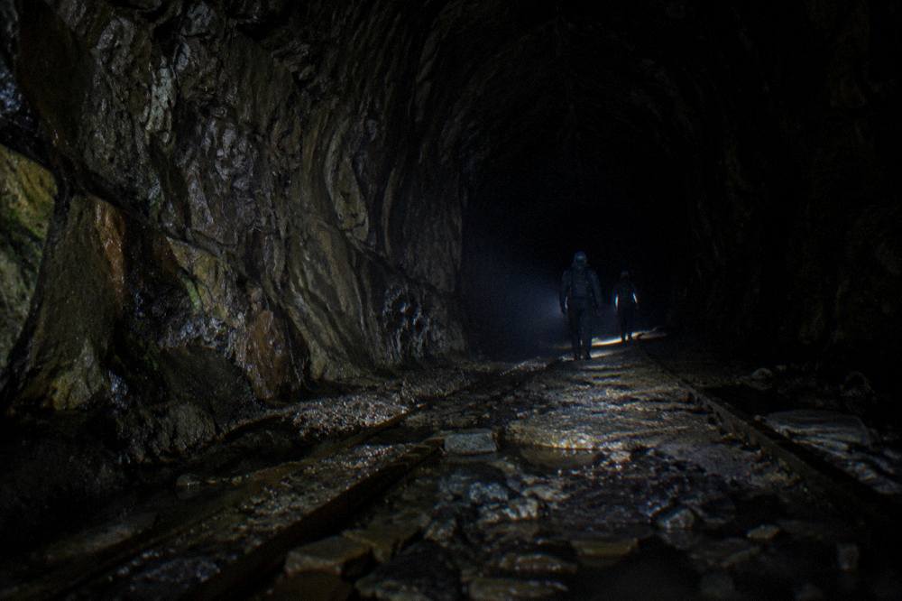A long dark disused railway tunnel with rough stone walls receding into blackness