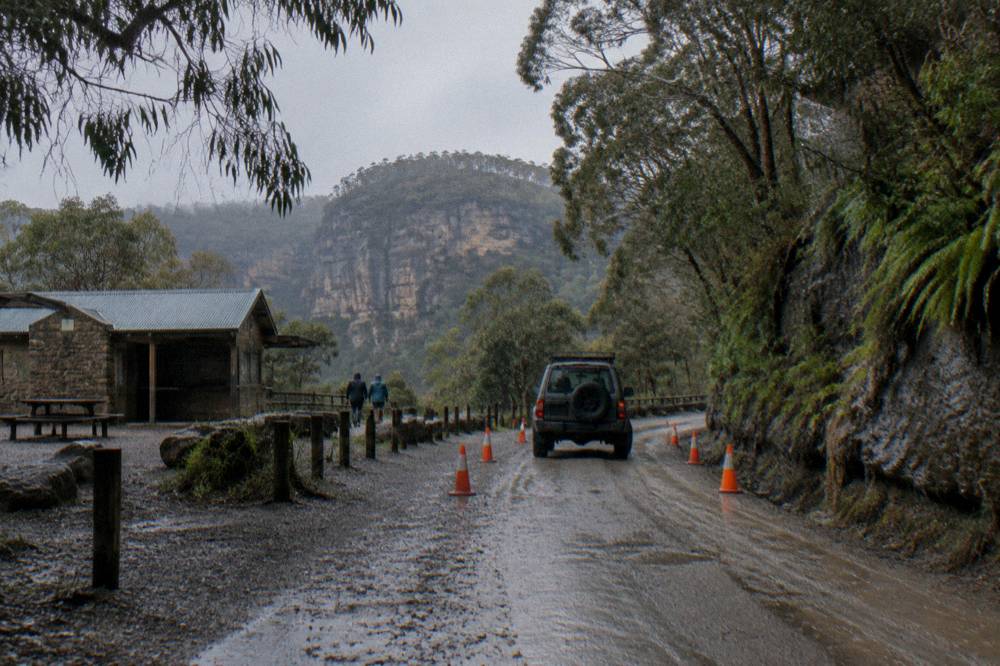 Traffic control signs and a single lane of gravel road through roadworks in forest
