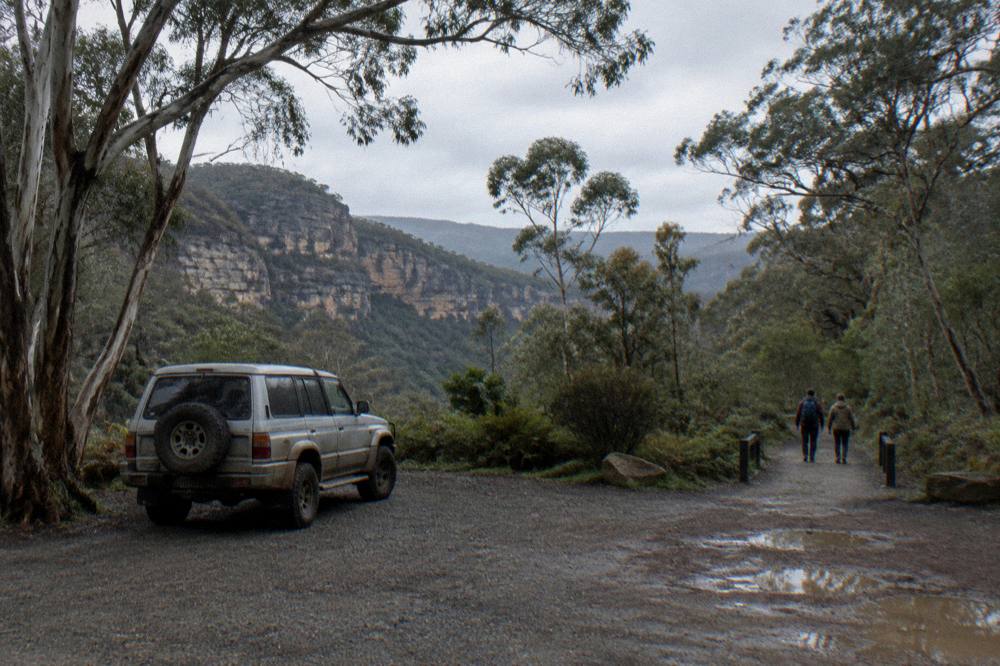 A quiet gravel carpark surrounded by eucalypt forest on an overcast weekday morning