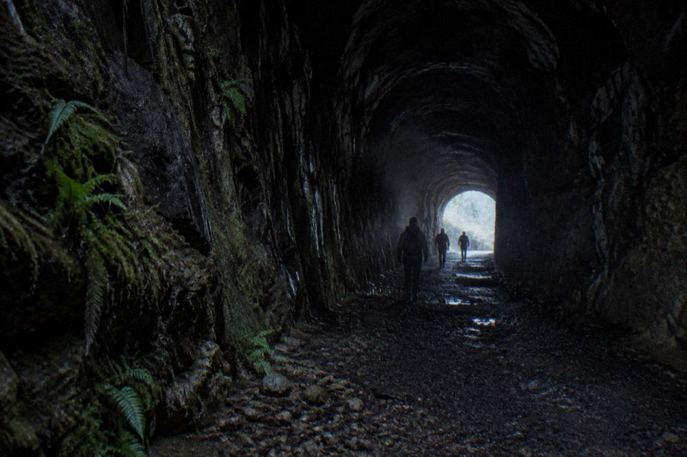 A dark railway tunnel interior with a faint glow of light at the far end