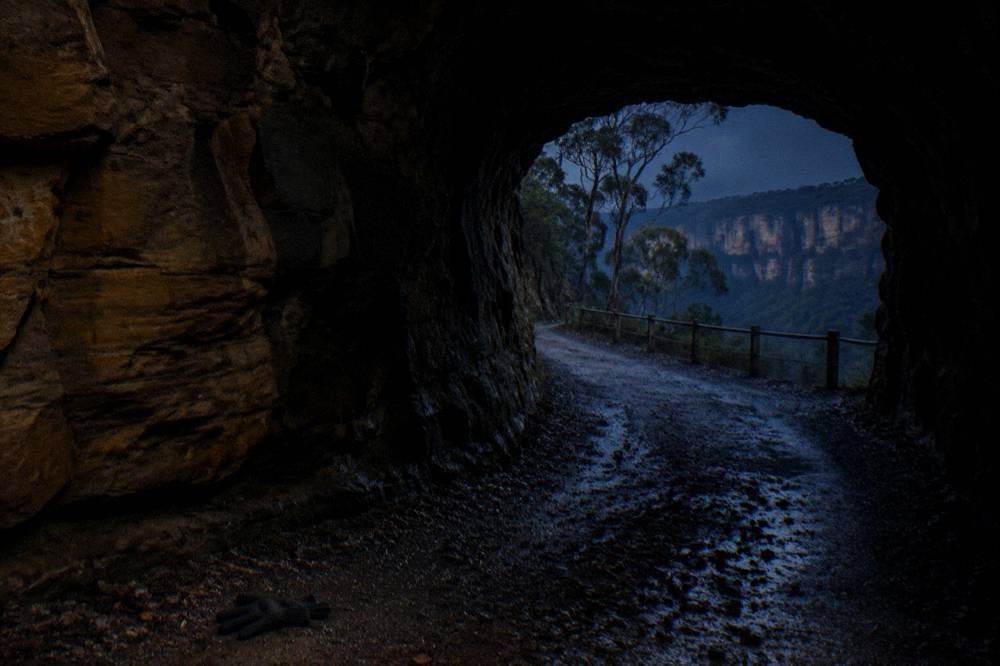 A dark sandstone tunnel interior with faint light at the far end