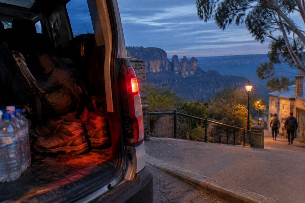 Headlamps and hiking boots packed in the back of a small tour van at dusk