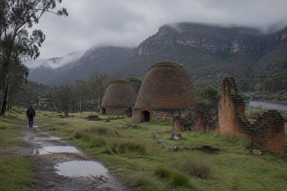 Stone beehive kilns and ruined brick walls in an open grassy valley