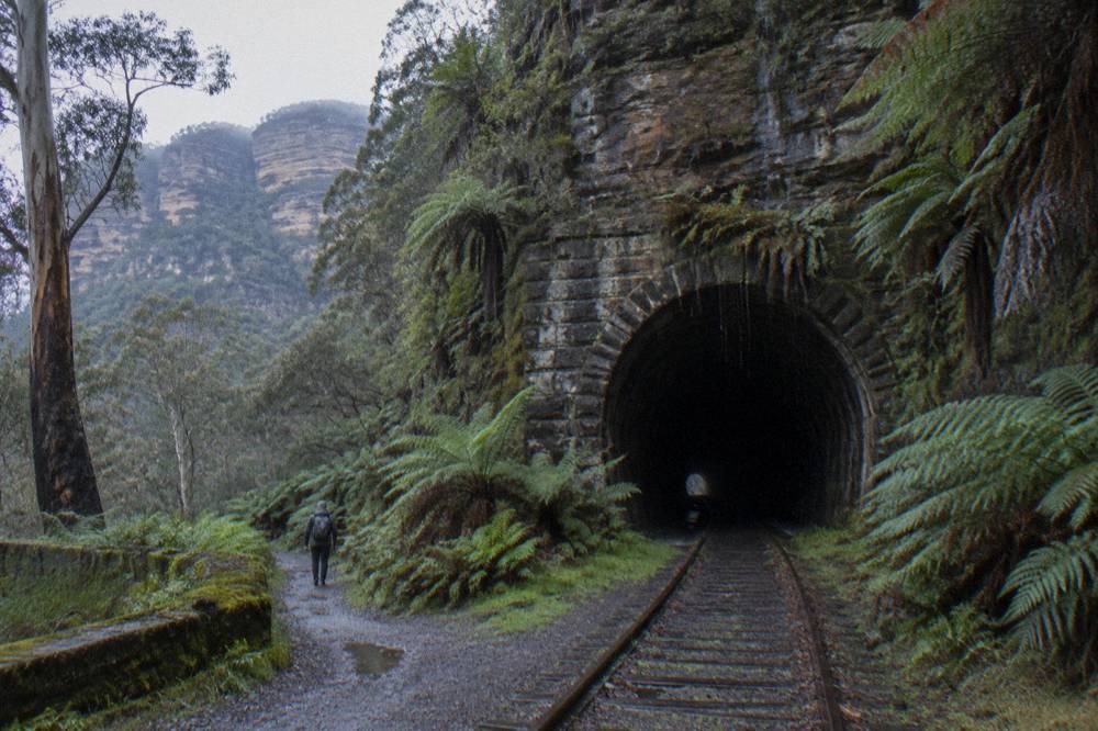 A dark curved railway tunnel entrance cut into a sandstone cliff face