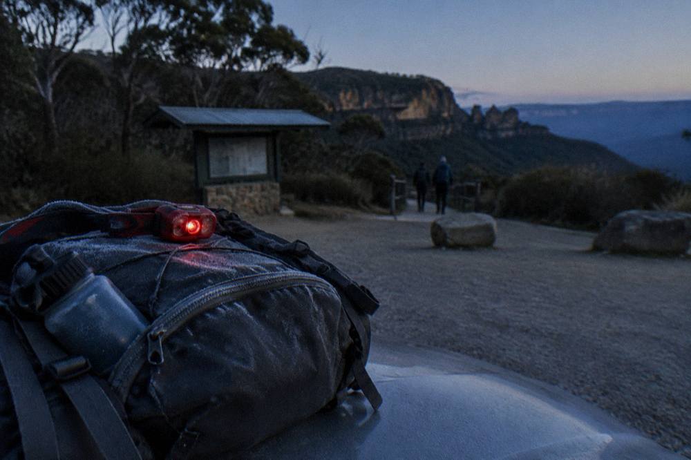A red-light headlamp and a water bottle packed on top of a hiking backpack