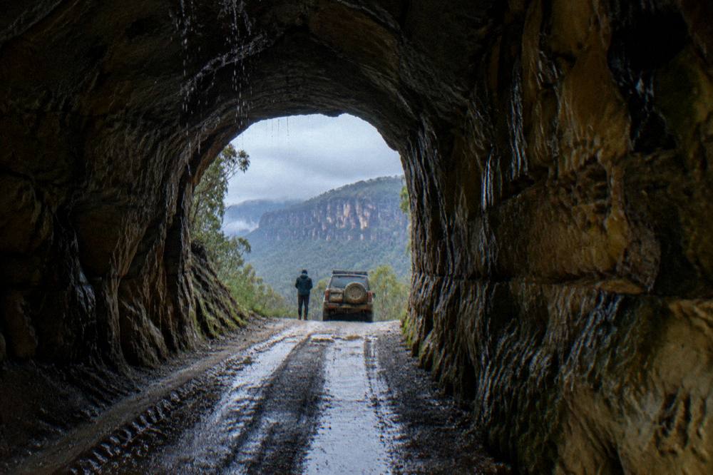 A narrow single-lane gravel tunnel through sandstone that vehicles pass through on the way to the glow worm track