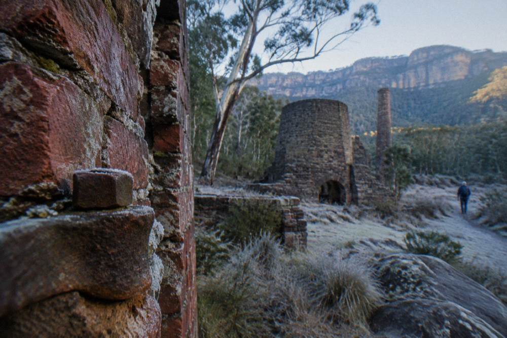 Weathered stone ruins of industrial kilns among trees at Newnes